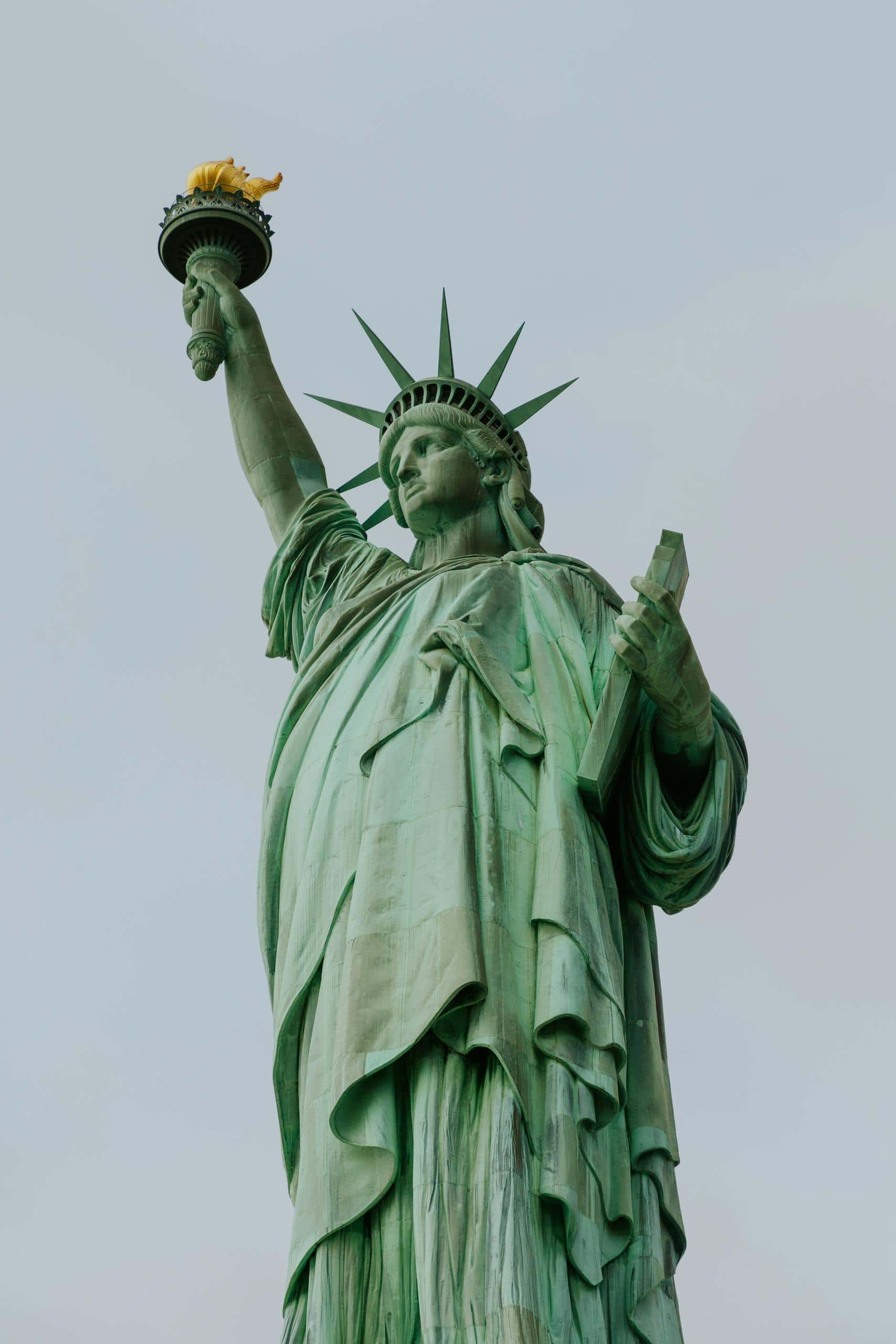 The Statue of Liberty standing majestically against a clear sky, symbolizing freedom and democracy.