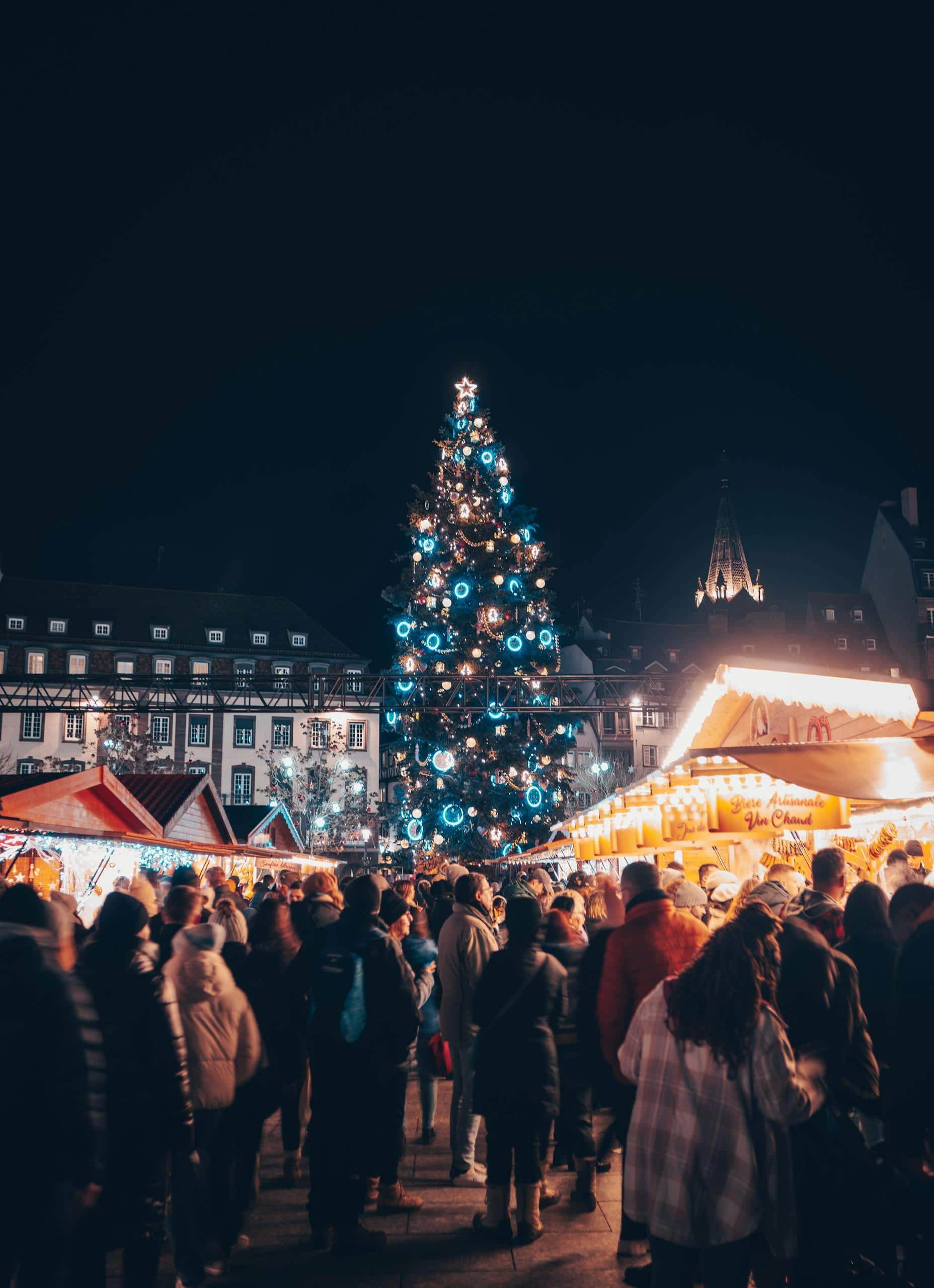 Lively Christmas market in Strasbourg's city center with festive lights and a towering tree.