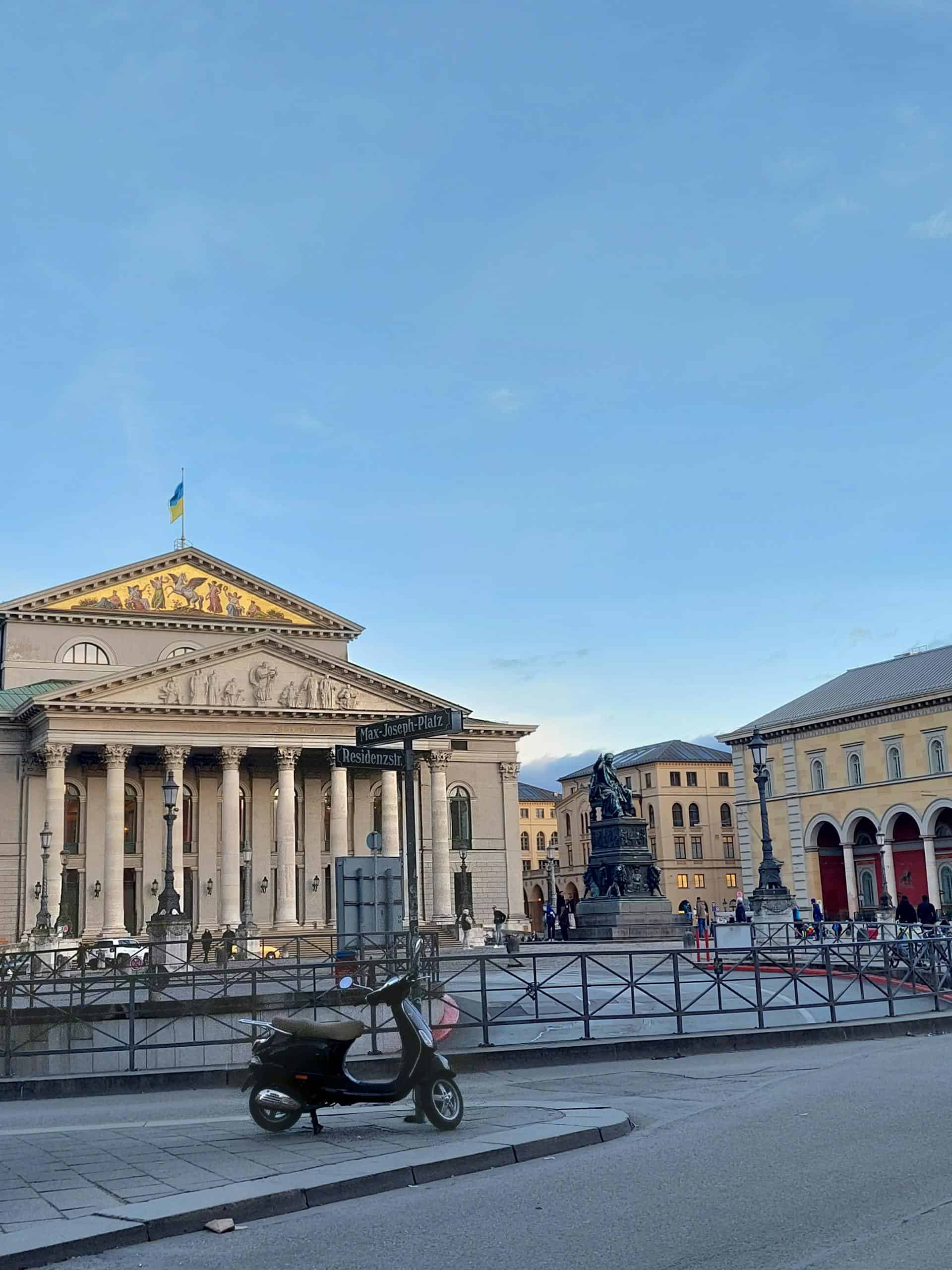 Scenic view of the Bavarian State Opera and nearby landmarks in Munich under a clear blue sky.