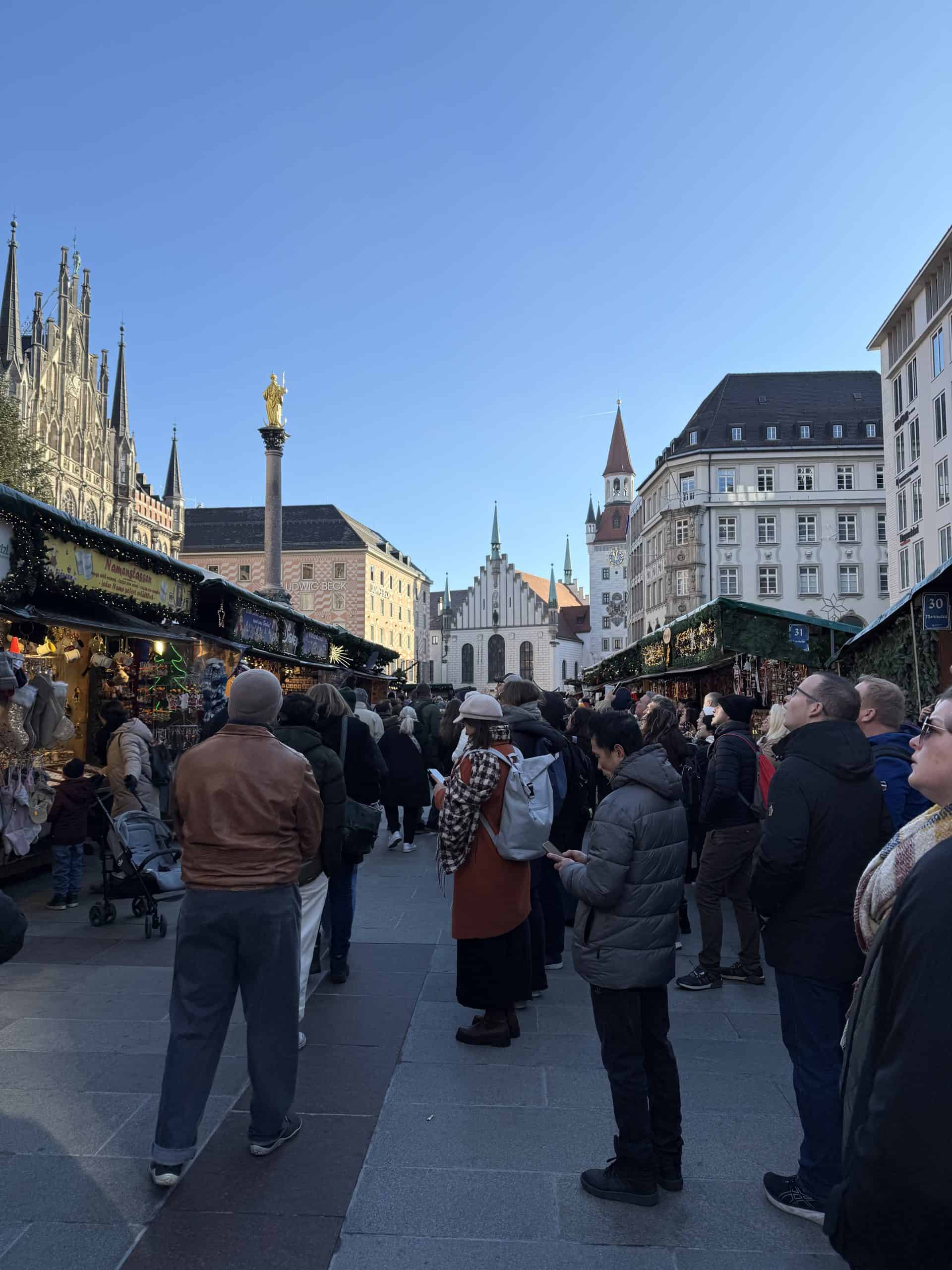Crowds watching Glockenspiel show among Christmas market stalls, Munich Germany