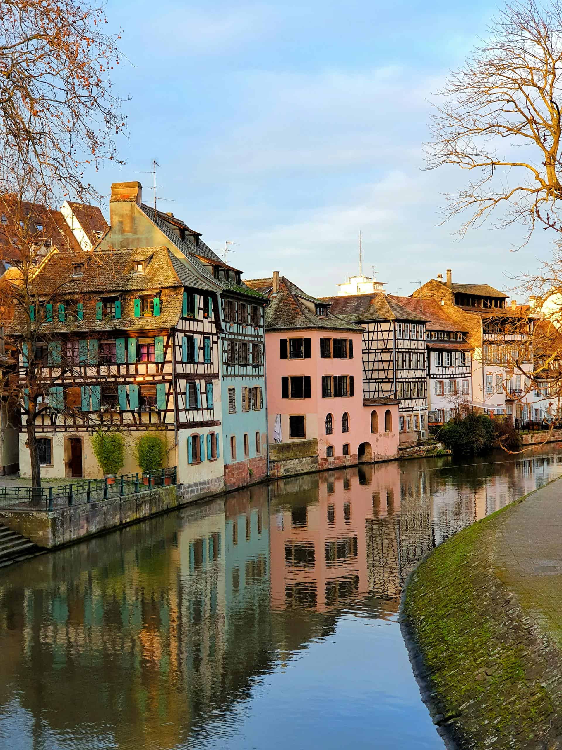 Beautiful canal view in Strasbourg featuring colorful half-timbered houses reflecting on the water.