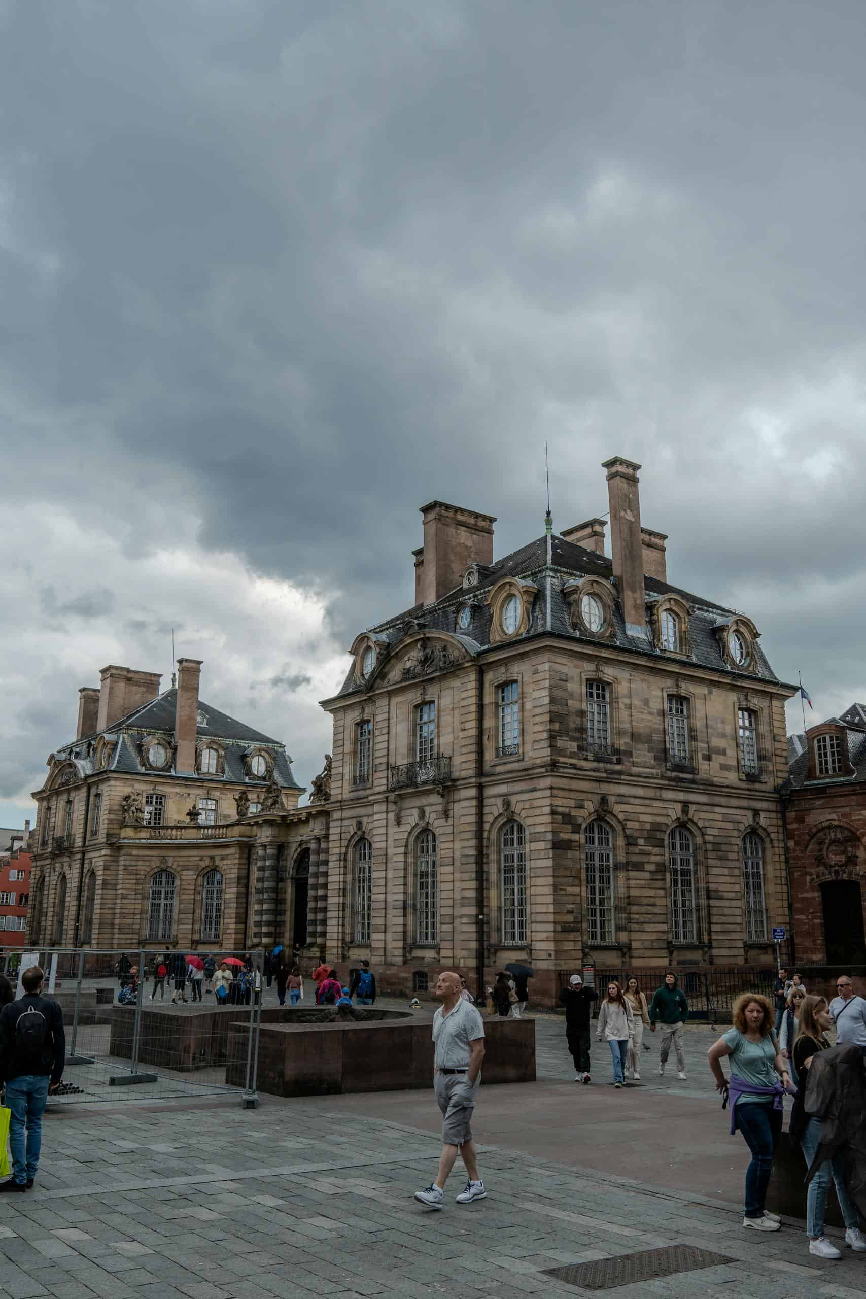 Explore the historic Palais Rohan in Strasbourg, France, with dramatic clouds enhancing its majestic architecture.