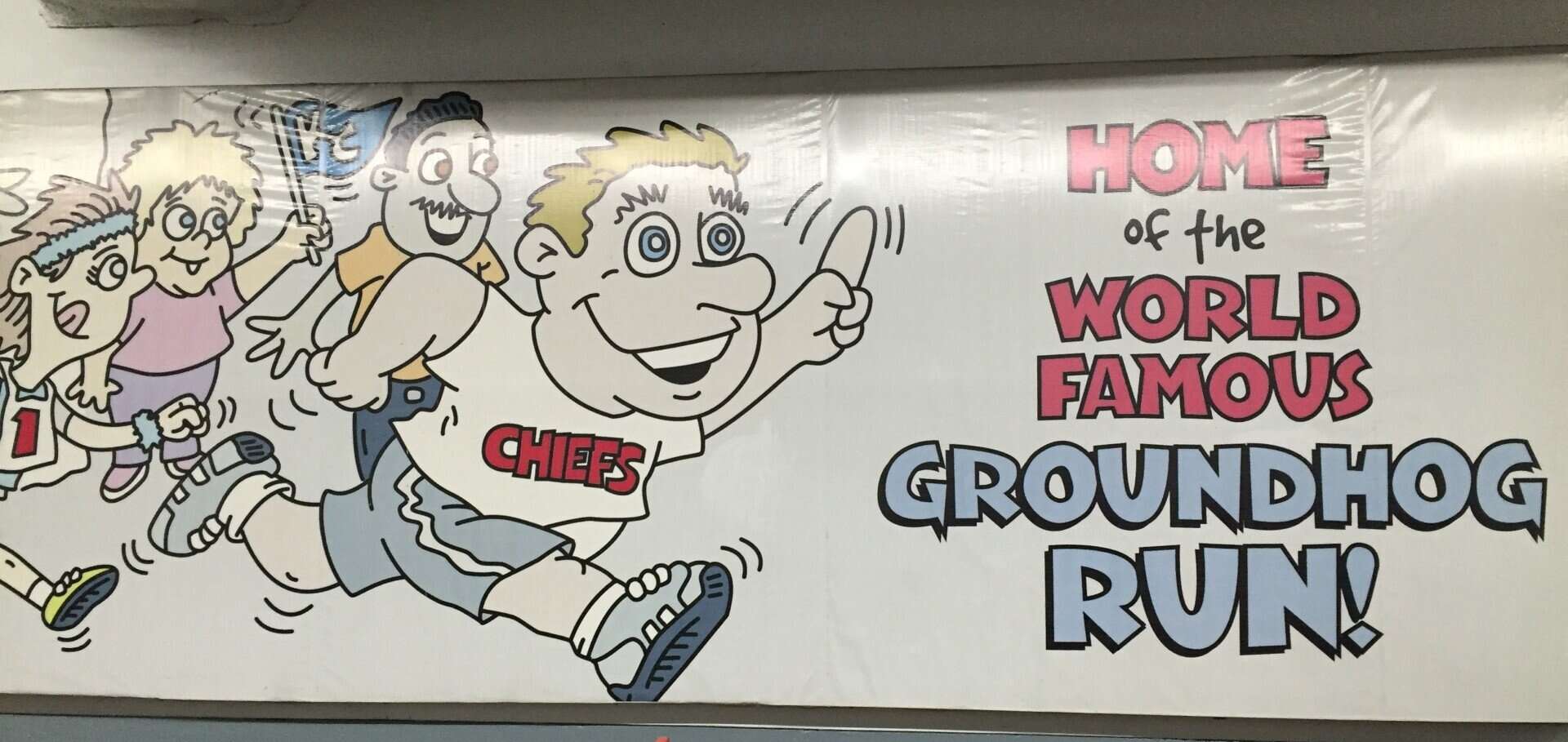 Colorful cartoon kids running on wall mural with "Home of the World Famous Groundhog Run" text.