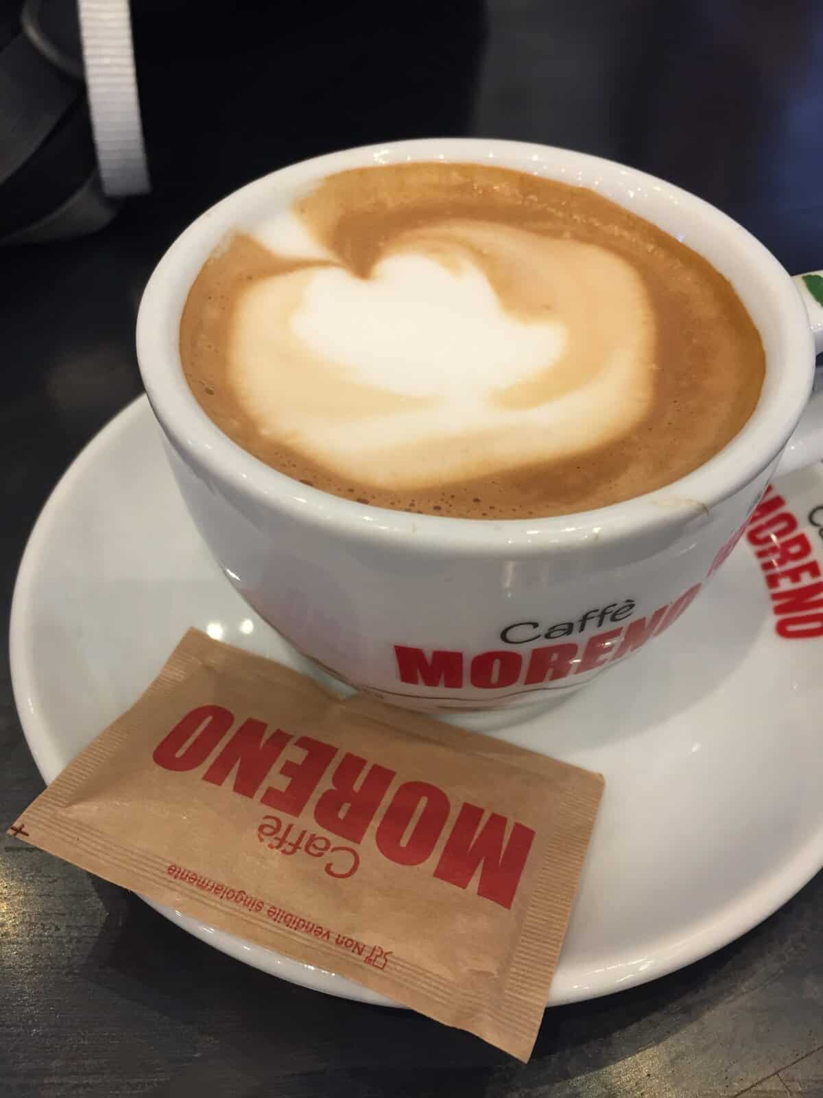 Cappuccino with latte art served at Caffè Moreno in Bologna, Italy, with sugar packet on the saucer.