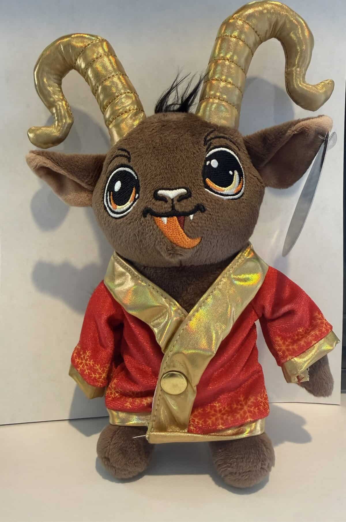 Cute Krampus plush toy wearing a red festive outfit with gold horns