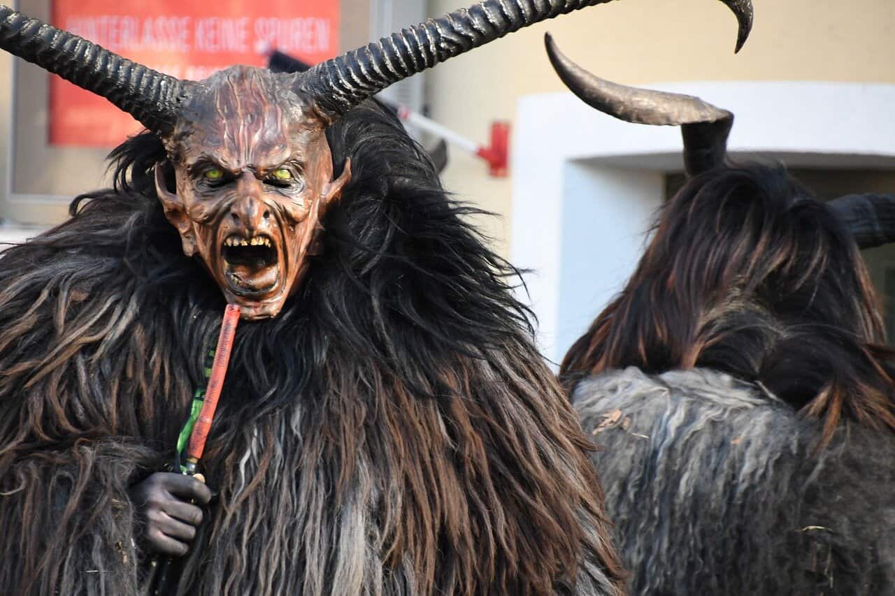 Perchten figures wearing traditional horned masks and fur costumes during an Alpine winter festival