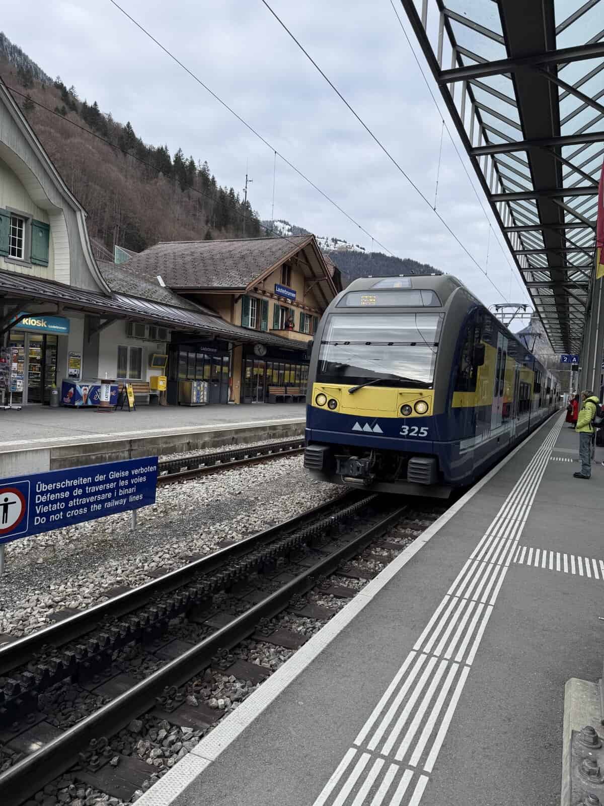 Swiss regional train arriving at a mountain station in Lauterbrunnen, Switzerland, with alpine scenery and historic station buildings