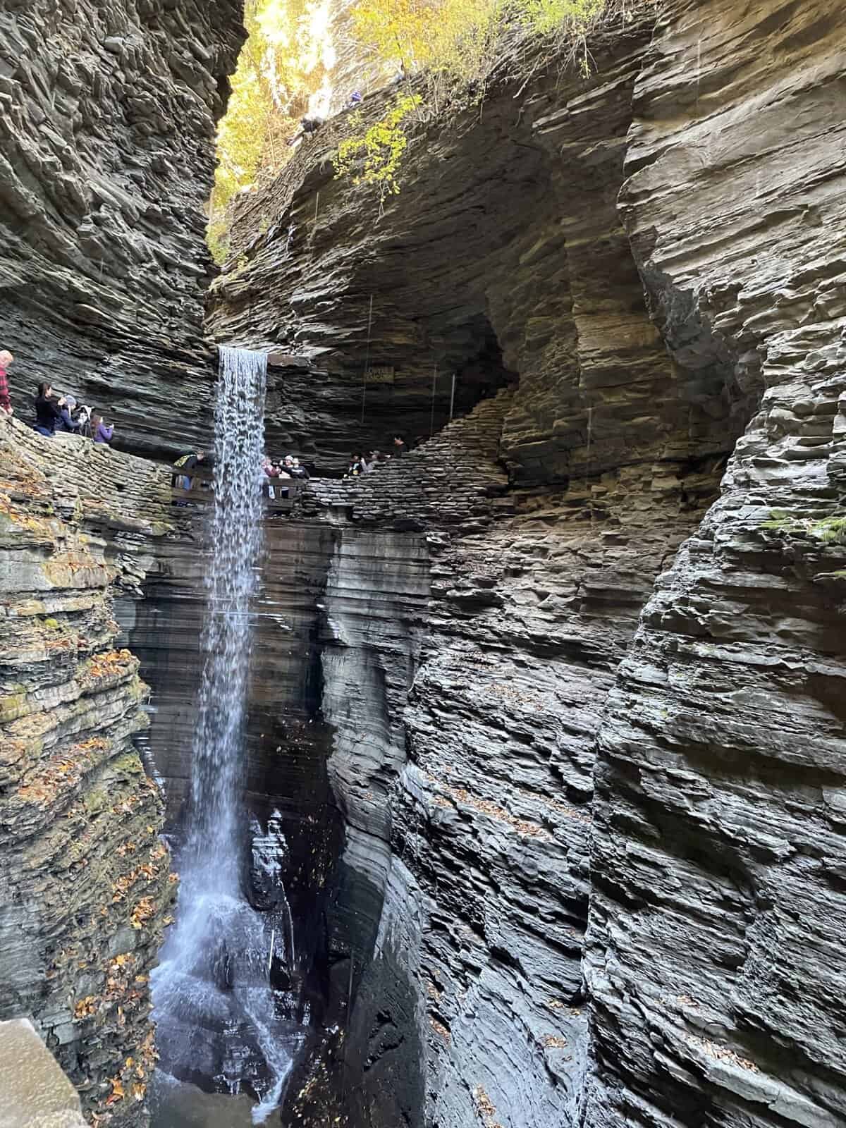 Waterfall along the Gorge Trail at Watkins Glen State Park in New York flowing through narrow rock walls with visitors on stone walkways