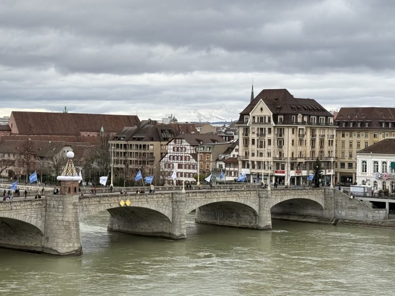 Colorful historic buildings along the Rhine River in Basel, Switzerland under cloudy winter skies