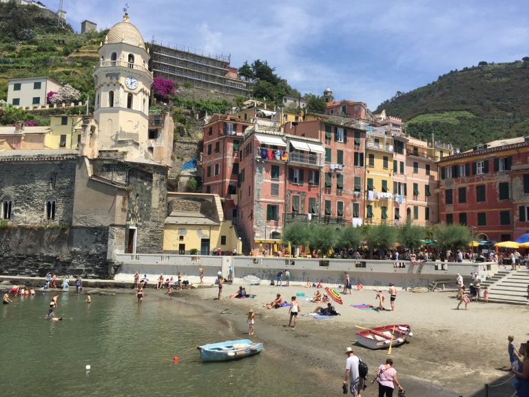 Vernazza beach in Cinque Terre Italy with pastel buildings and historic church overlooking the Ligurian Sea