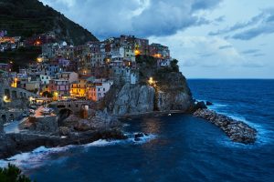 Manarola at sunset in Cinque Terre Italy with colorful cliffside houses glowing above the Ligurian Sea