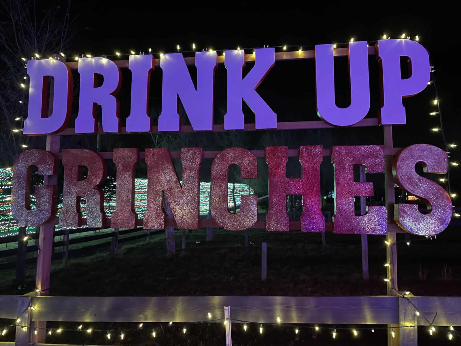 Drink Up Grinches sign at KC Wine Co. holiday light display near Kansas City at night