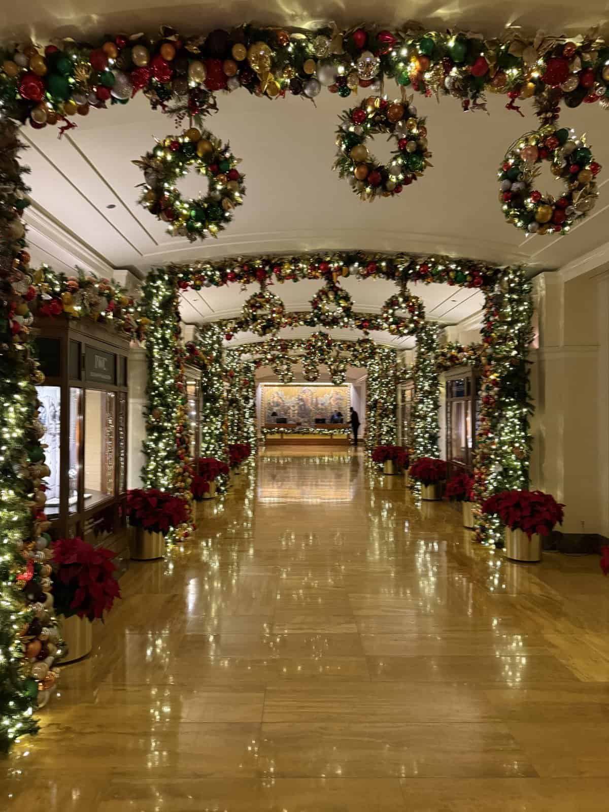 Peninsula Chicago hallway covered in Christmas garlands, wreaths, and lights with poinsettias lining the floor