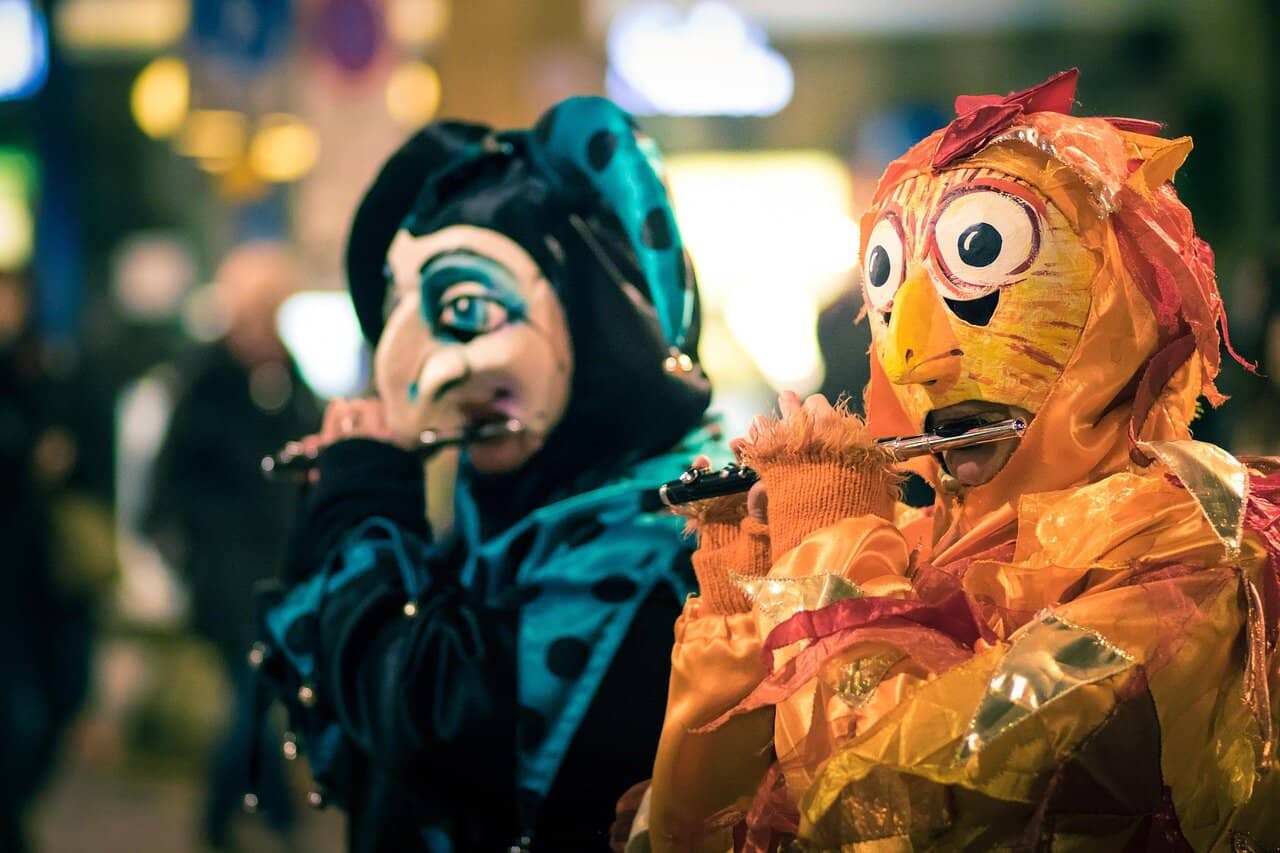 Colorful masked performers playing piccolos during Basel Carnival at night, wearing traditional Fasnacht costumes in Switzerland