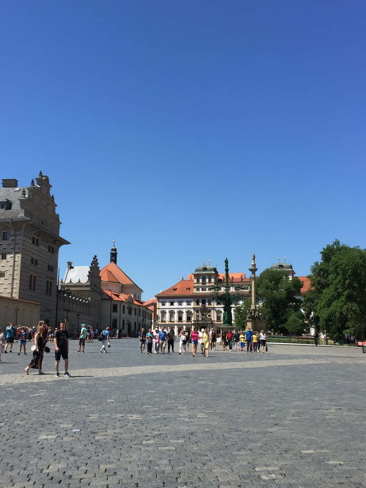 Visitors walking across the large square in front of Prague Castle.