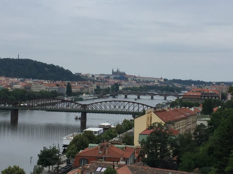 View of Prague skyline and bridges over the Vltava River with Prague Castle in the distance.