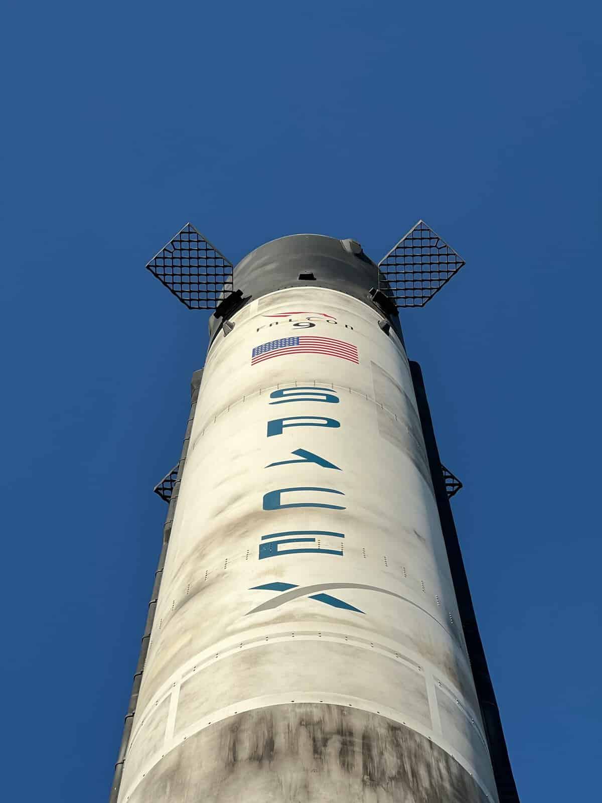 Close-up view of a SpaceX rocket against a clear blue sky, showcasing its structure and design.