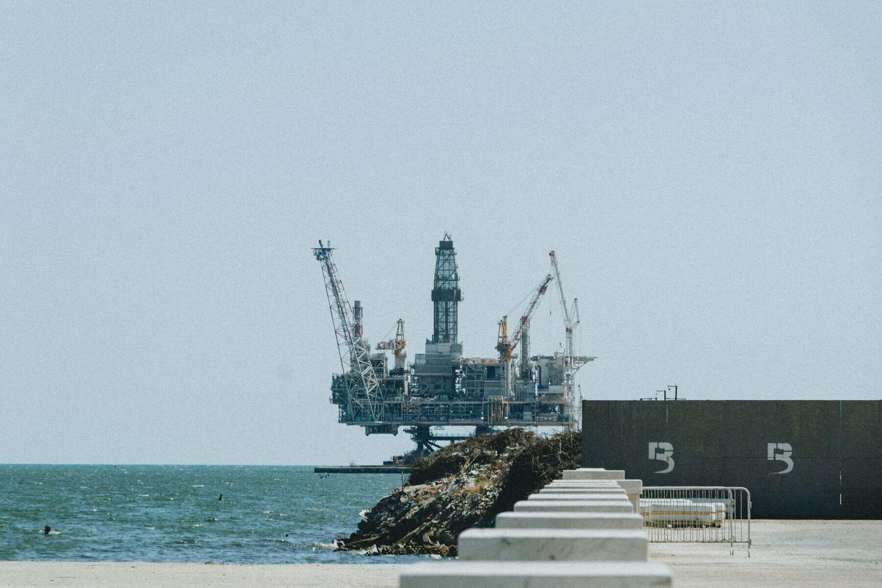 Distant view of an offshore oil rig with cranes on a sunny day.