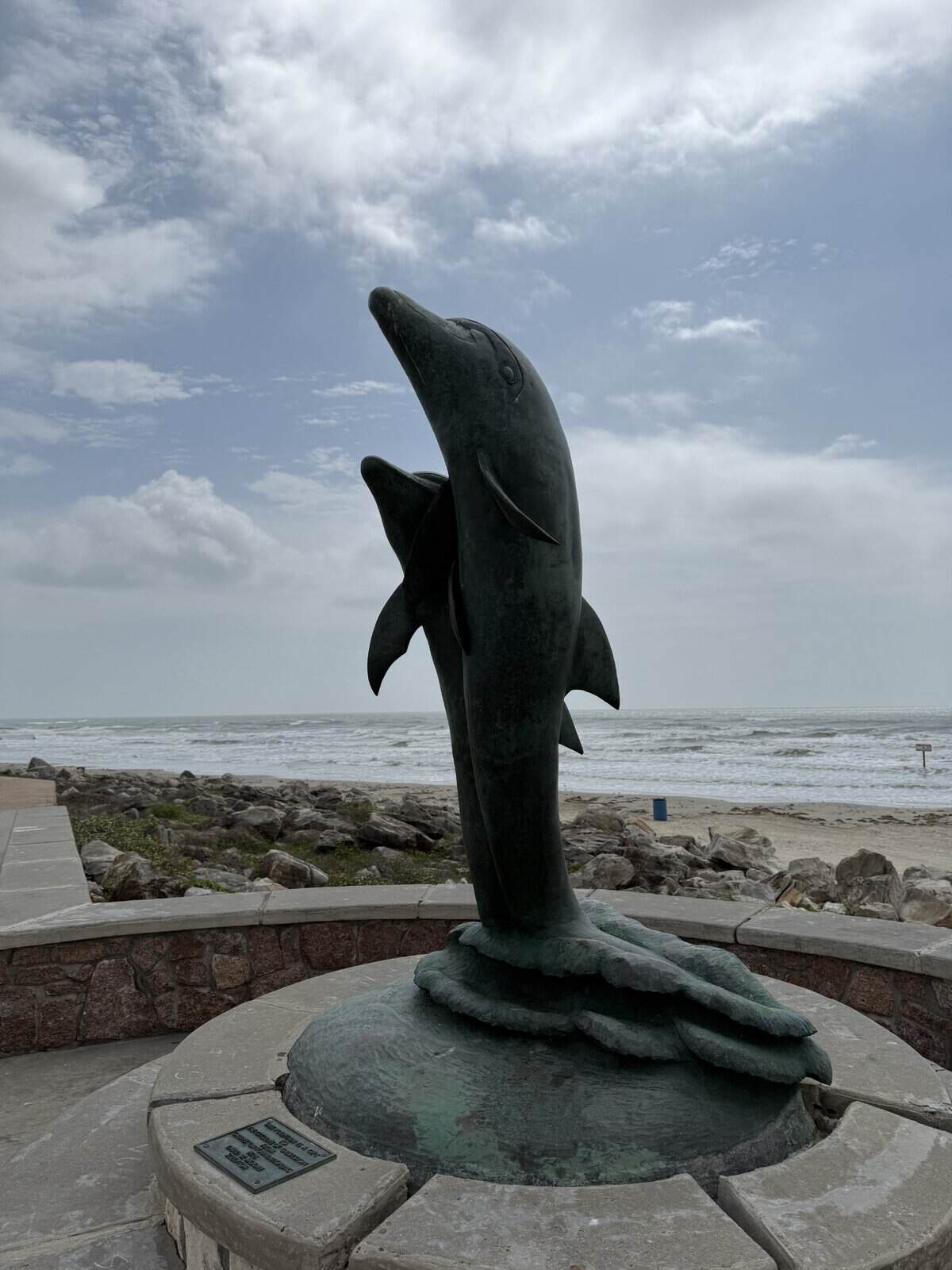 Dolphin statue along the Galveston Seawall overlooking the beach