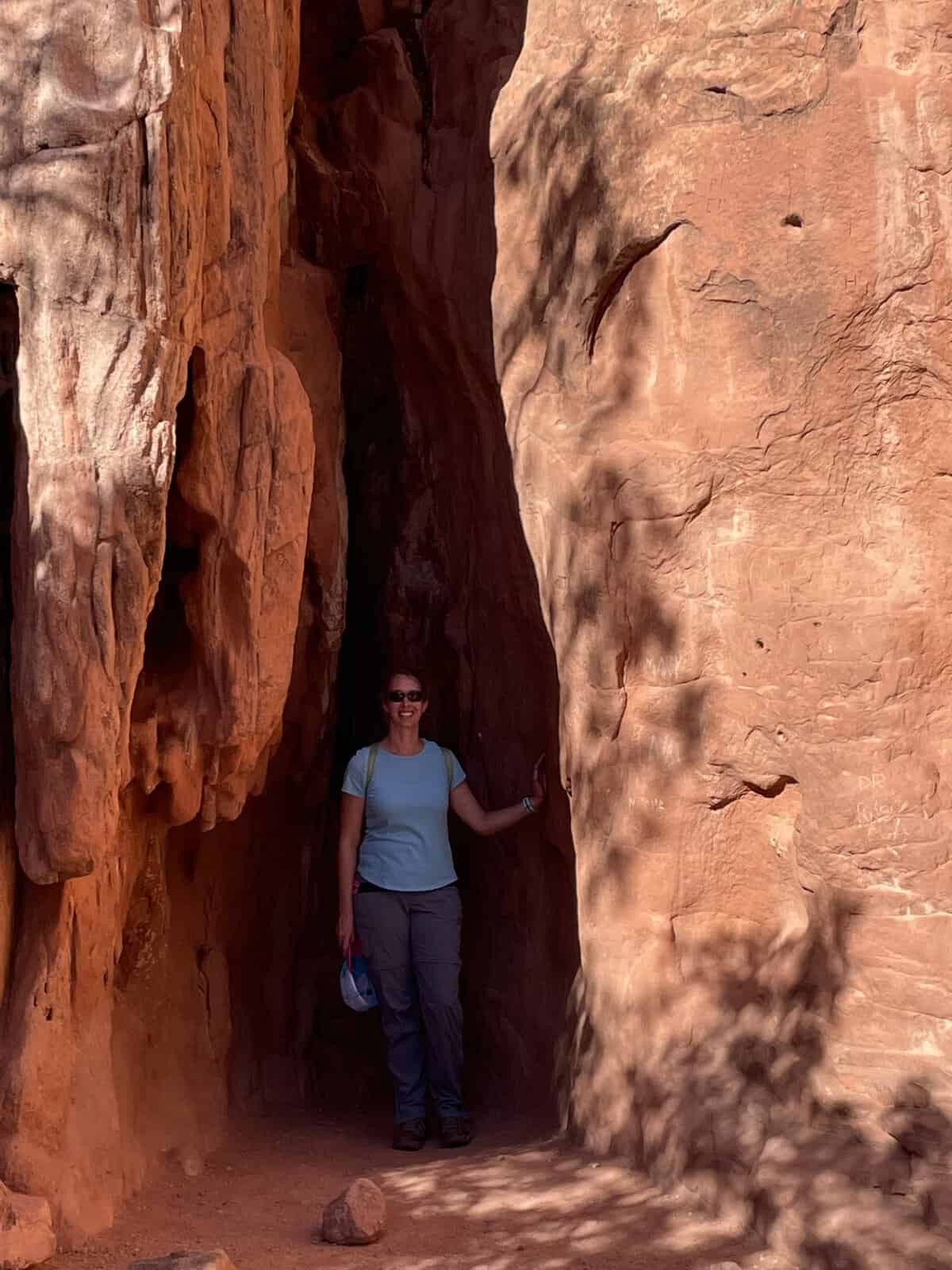 Woman standing in a narrow red rock canyon passage at Garden of the Gods in Colorado Springs, Colorado.