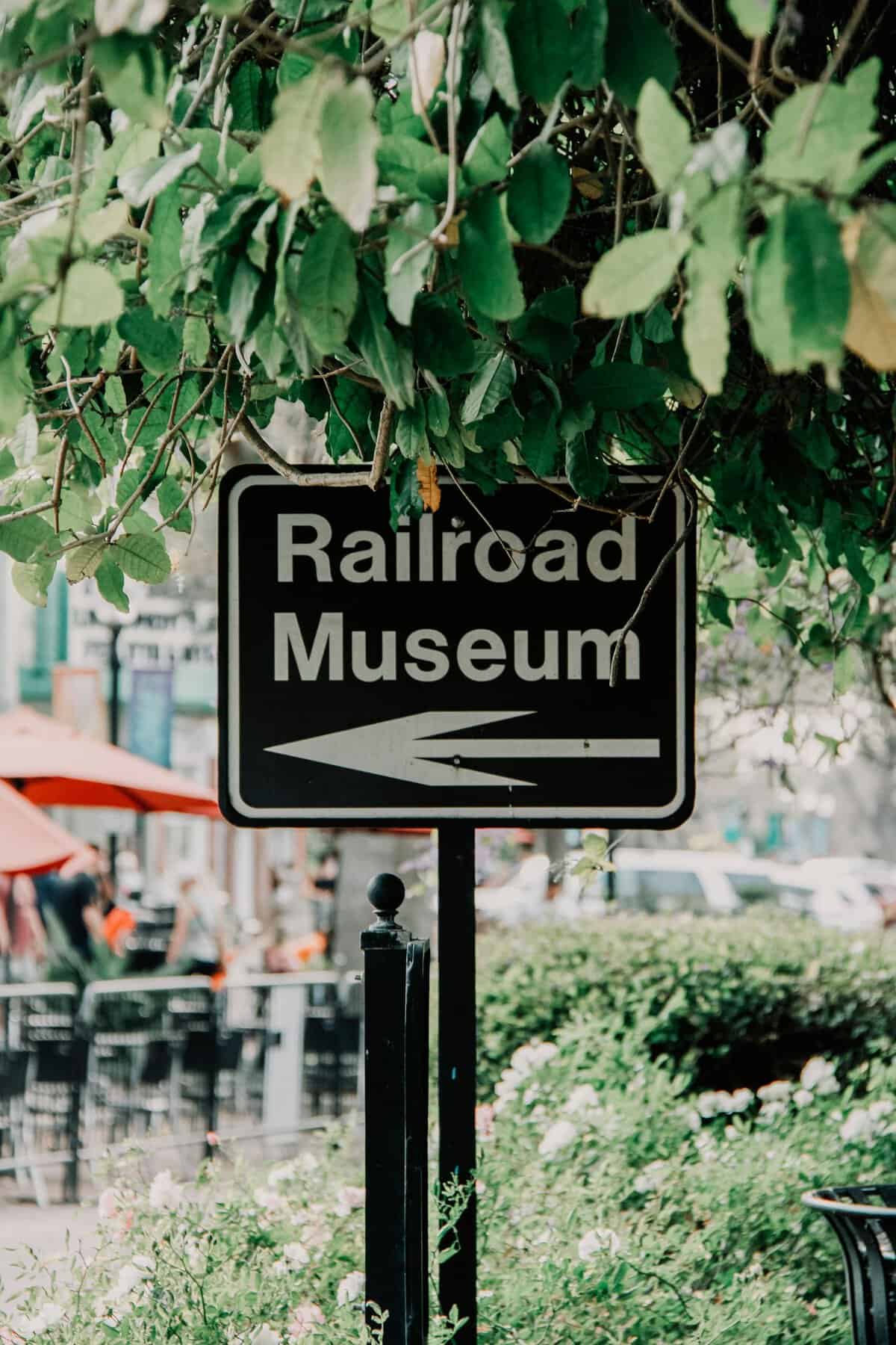 Urban photograph featuring a Railroad Museum sign surrounded by lush greenery.