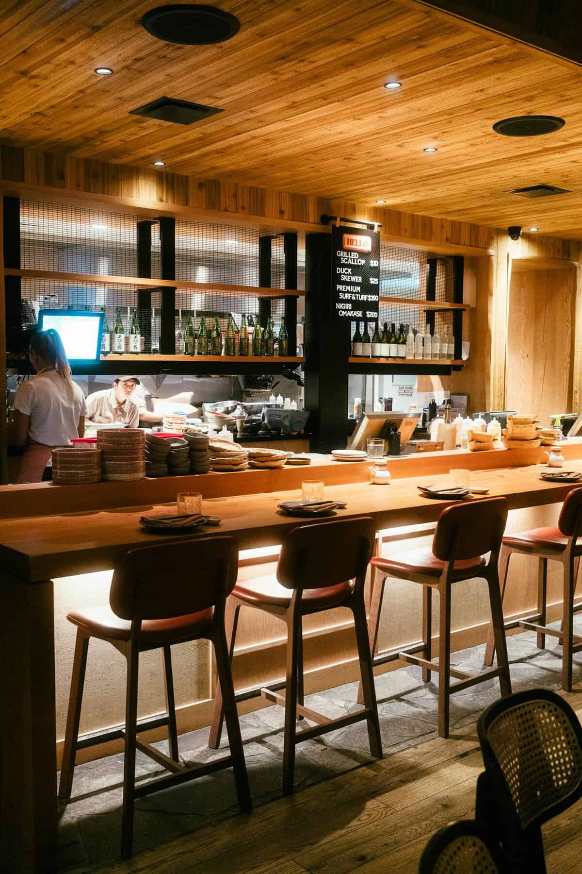 Warm and inviting rustic restaurant interior featuring a wooden bar with seating and soft lighting.