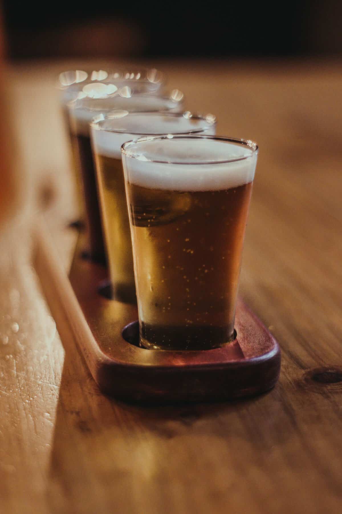 Close-up of craft beer flight on wooden table, showcasing assorted beers.
