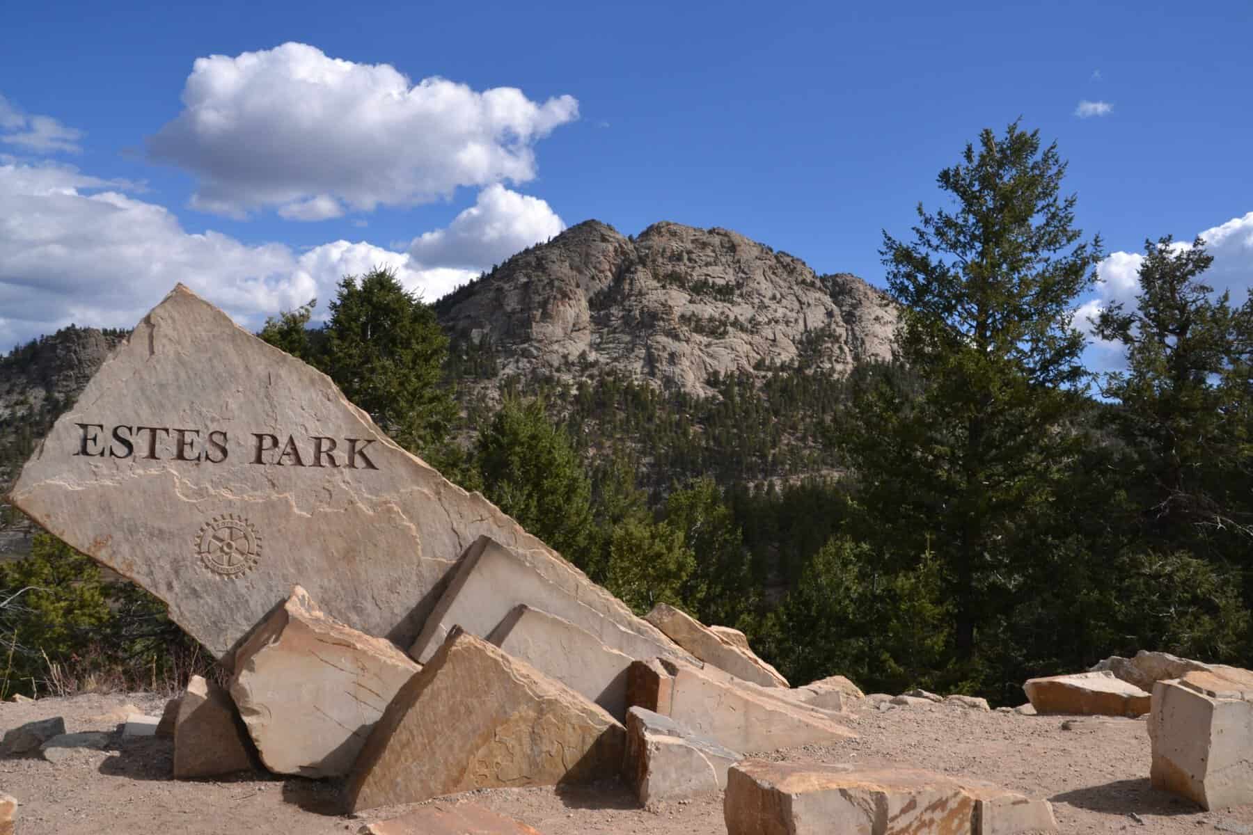 Welcome sign for Estes Park, Colorado, with Rocky Mountains in the background.