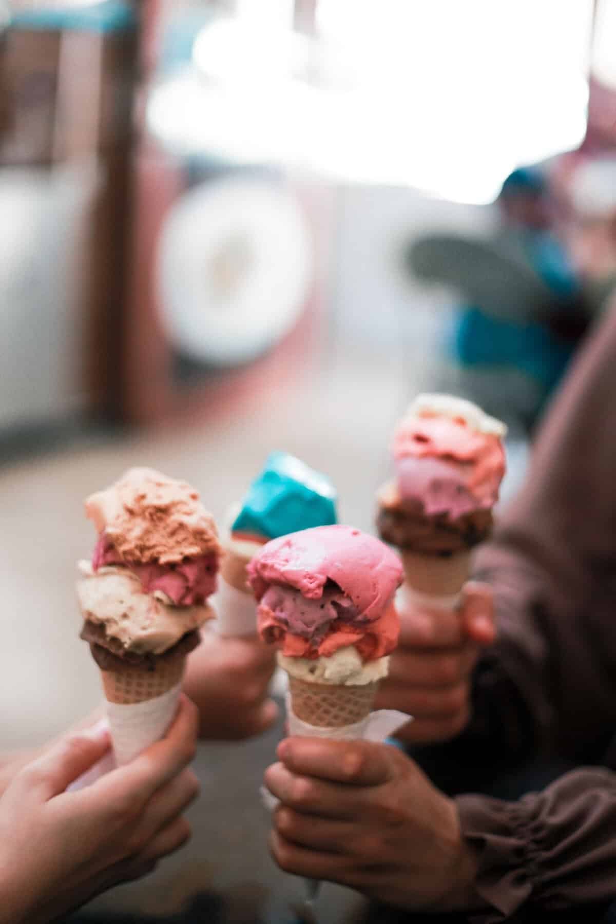 Hands holding vibrant ice cream cones creating a joyful summer vibe.