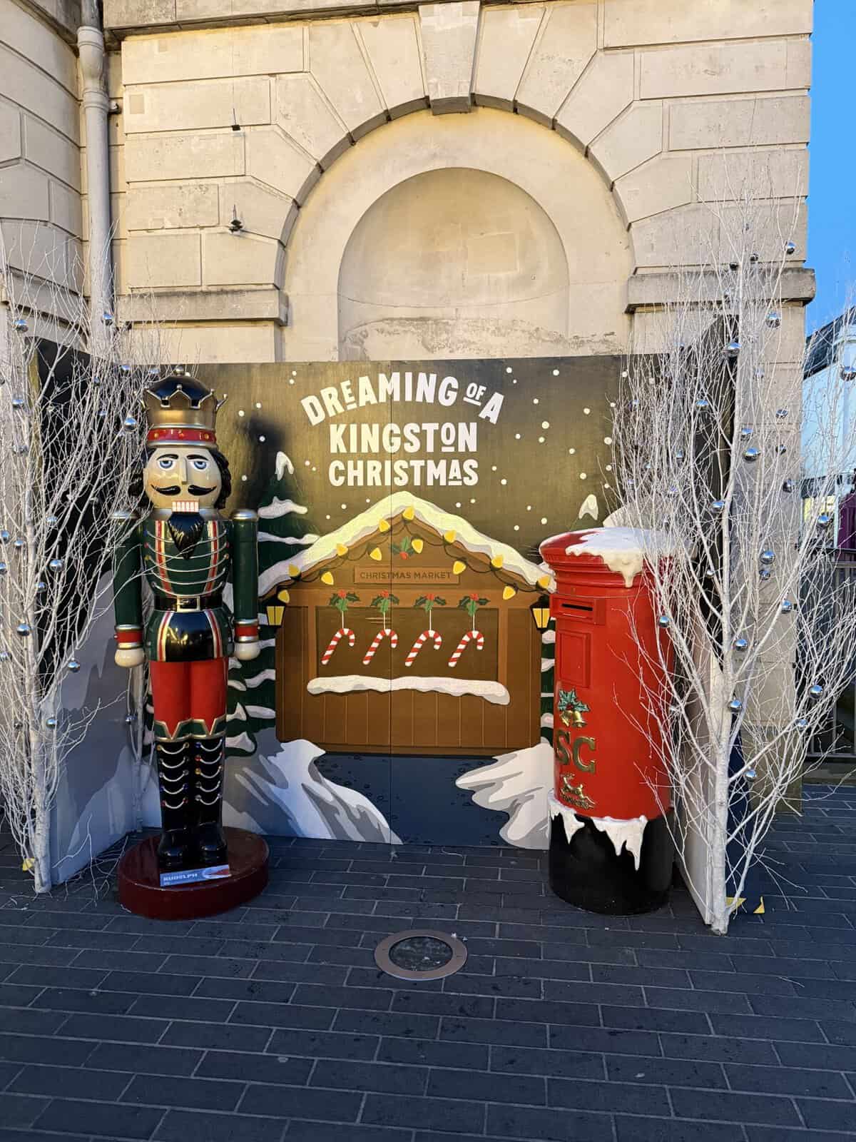 Christmas display in Kingston Upon Thames featuring a nutcracker statue, festive red post box, and “Dreaming of a Kingston Christmas” holiday backdrop.