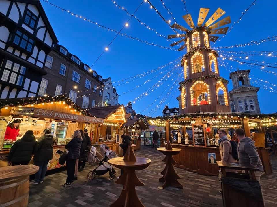 Kingston Christmas Market wooden stalls and illuminated Christmas pyramid during the evening in southwest London