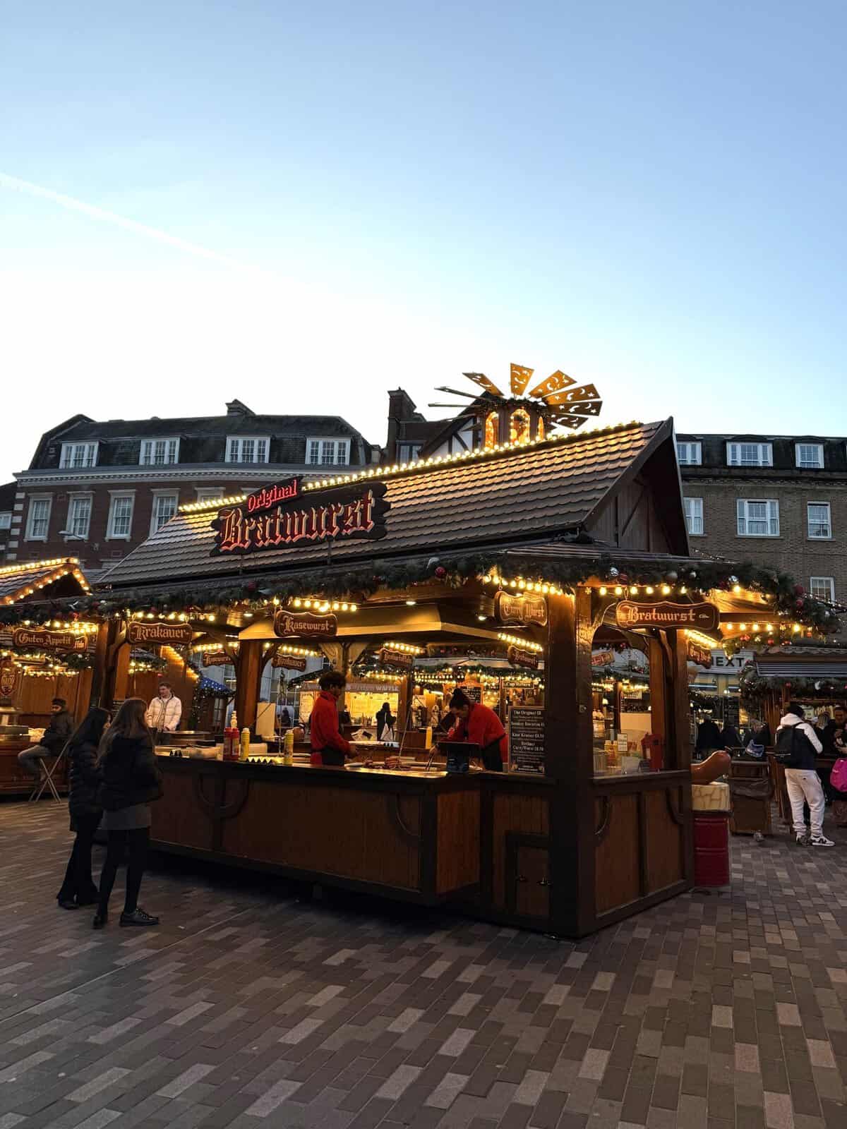 German style bratwurst food stall at Kingston Christmas Market with traditional wooden chalet design