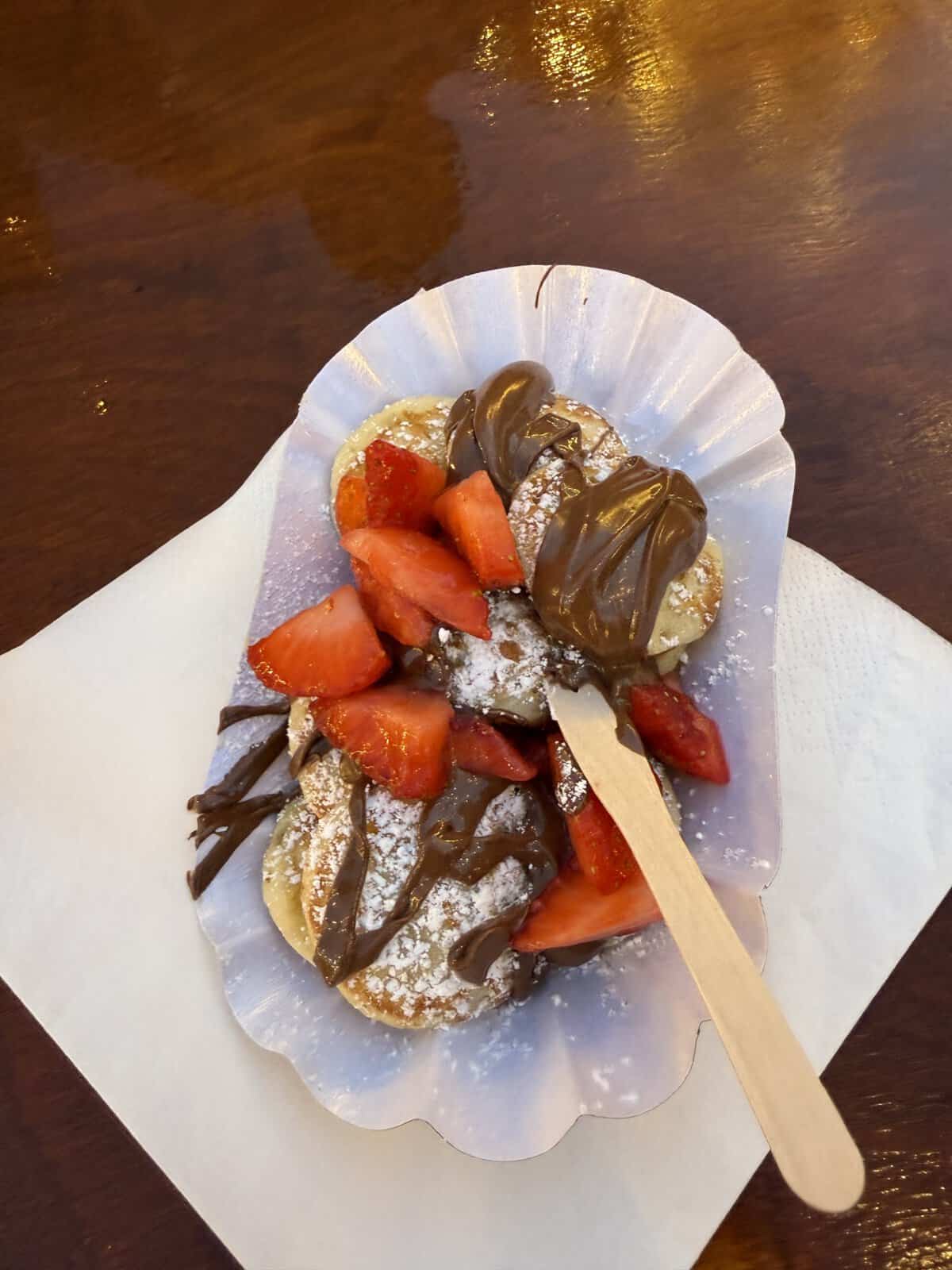 Mini pancakes topped with Nutella, strawberries, and powdered sugar at Kingston Christmas Market