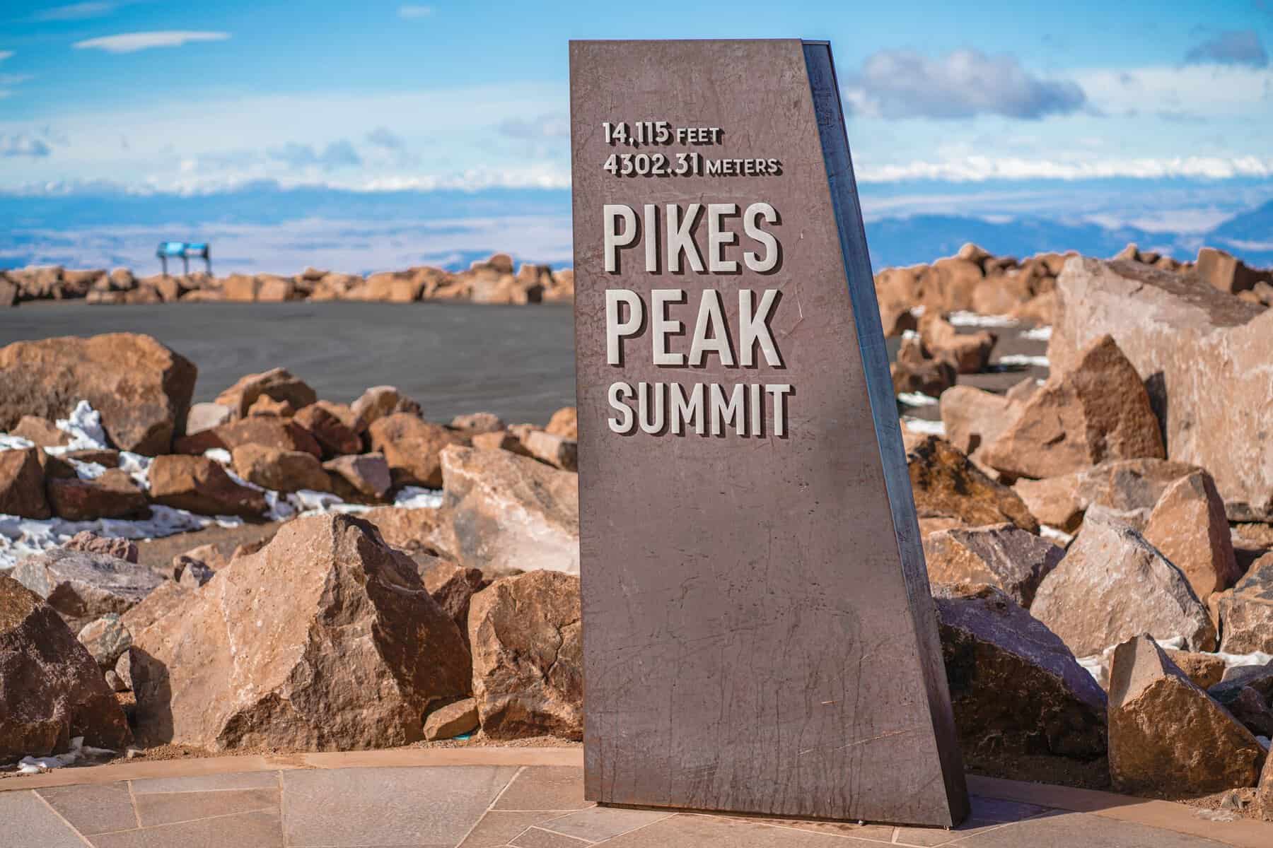 Scenic view of the Pikes Peak Summit sign surrounded by rocky terrain in Colorado.