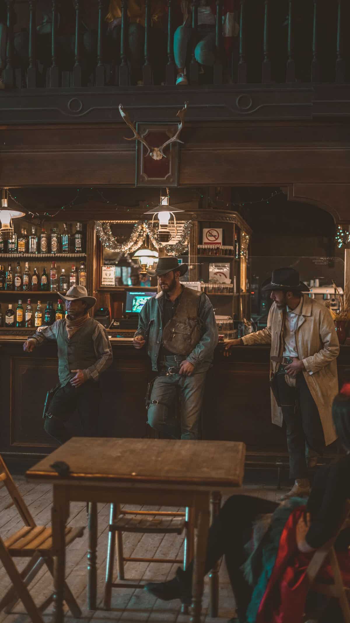 Three cowboys stand at a rustic saloon bar, capturing classic western ambiance.