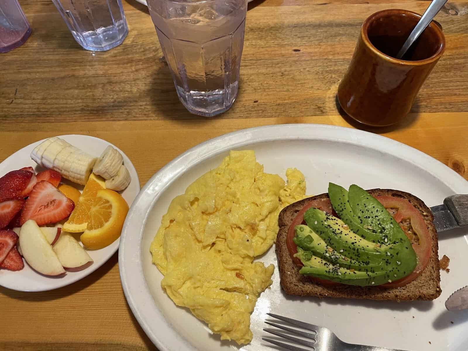 Breakfast with avocado toast, scrambled eggs, and fresh fruit at Top Notch Cafe in Estes Park.