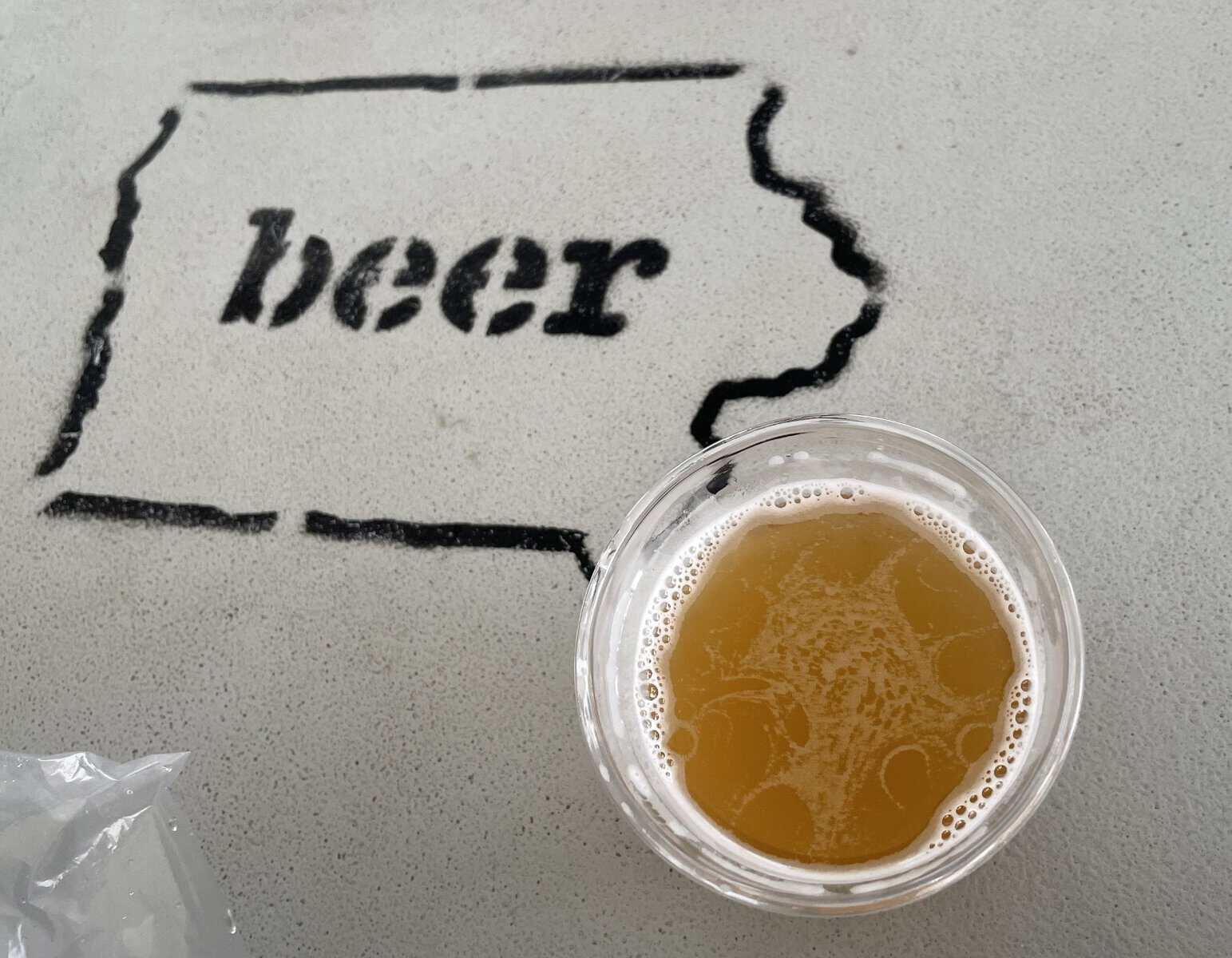 Glass of craft beer beside an Iowa beer map design