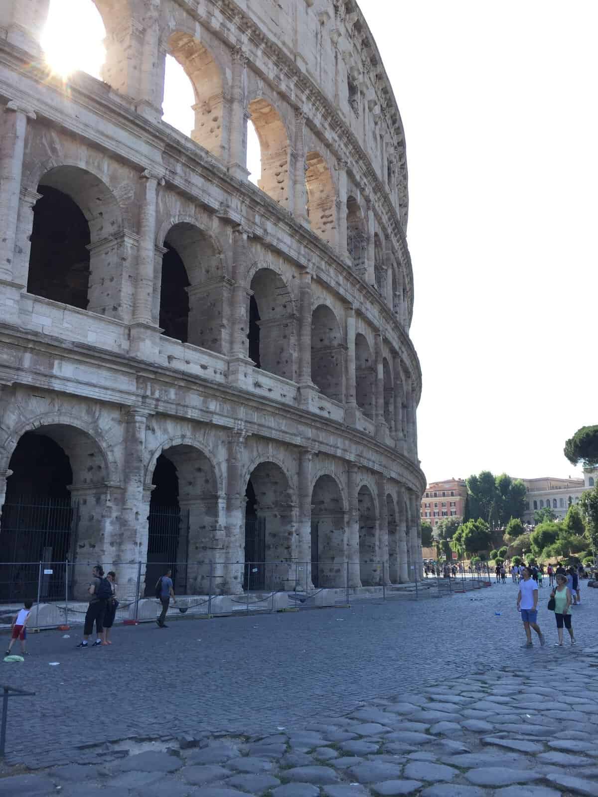Exterior arches of the Colosseum in Rome, Italy with cobblestone streets in the foreground