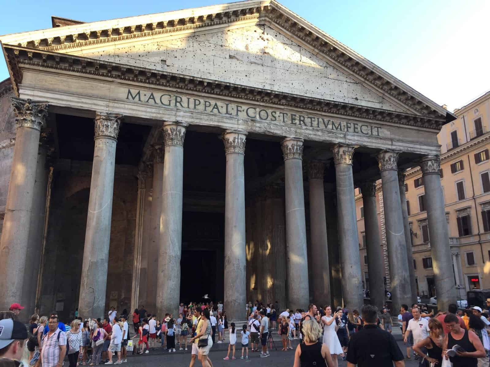 Ancient columns and exterior of the Pantheon in Rome with visitors gathered in the Piazza della Rotonda